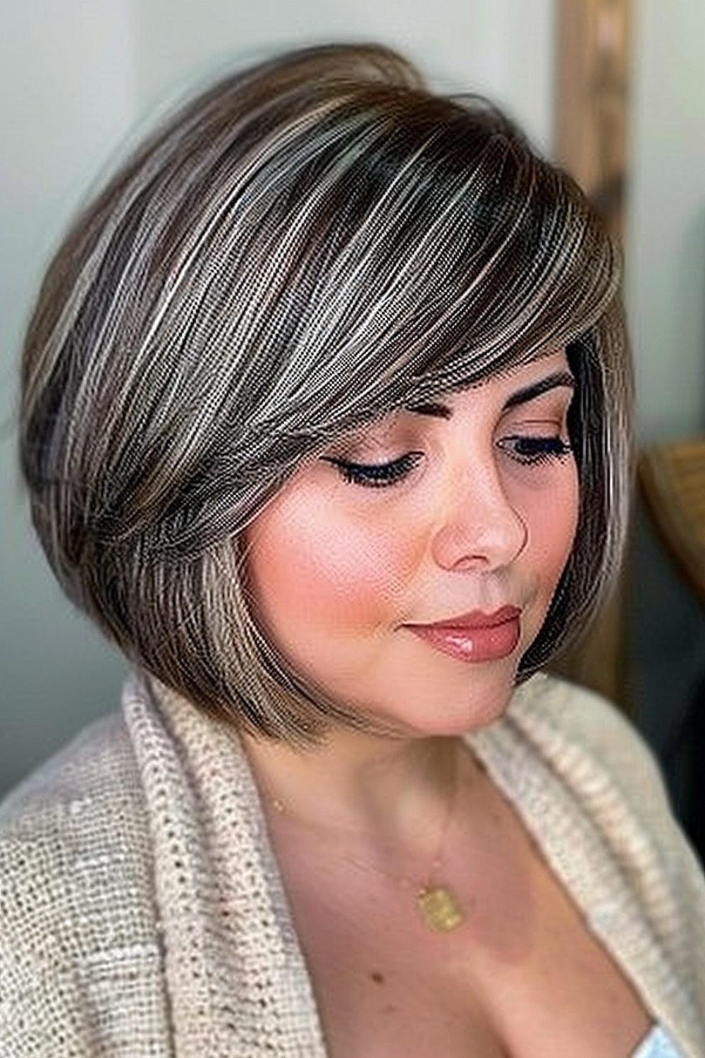 Woman with a swing bob and sweeping bangs in multi-tonal brown and ash blonde